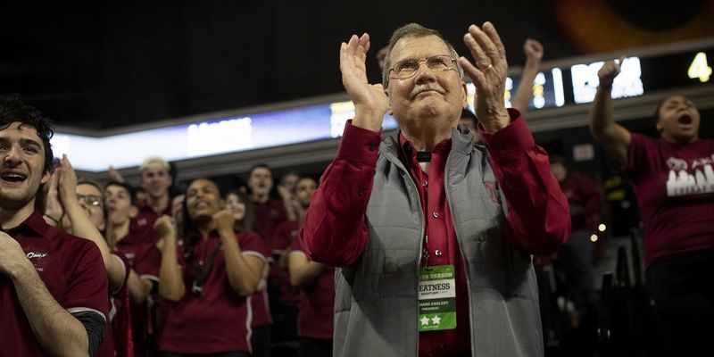 President Richard M. Englert clapping in the stands among Temple students at a basketball game. 