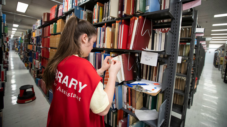 a student labeling books in Paley Library