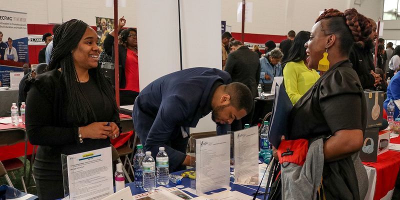 A group of people standing around a table during a job fair at Temple University.