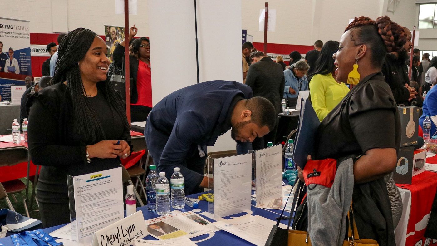 A group of people standing around a table during a job fair at Temple University.