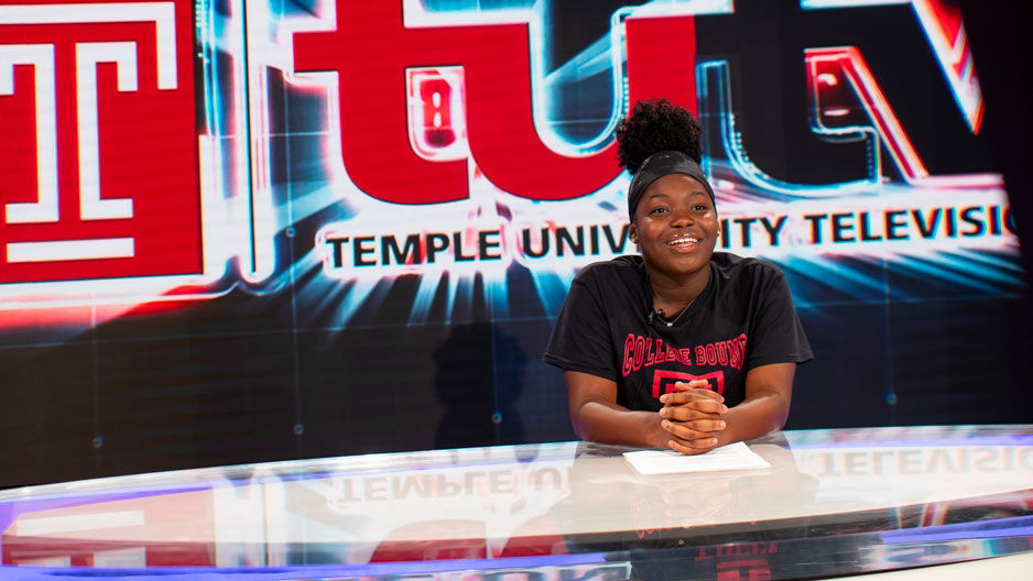 A teenage girl sitting at the anchor desk at TUTV