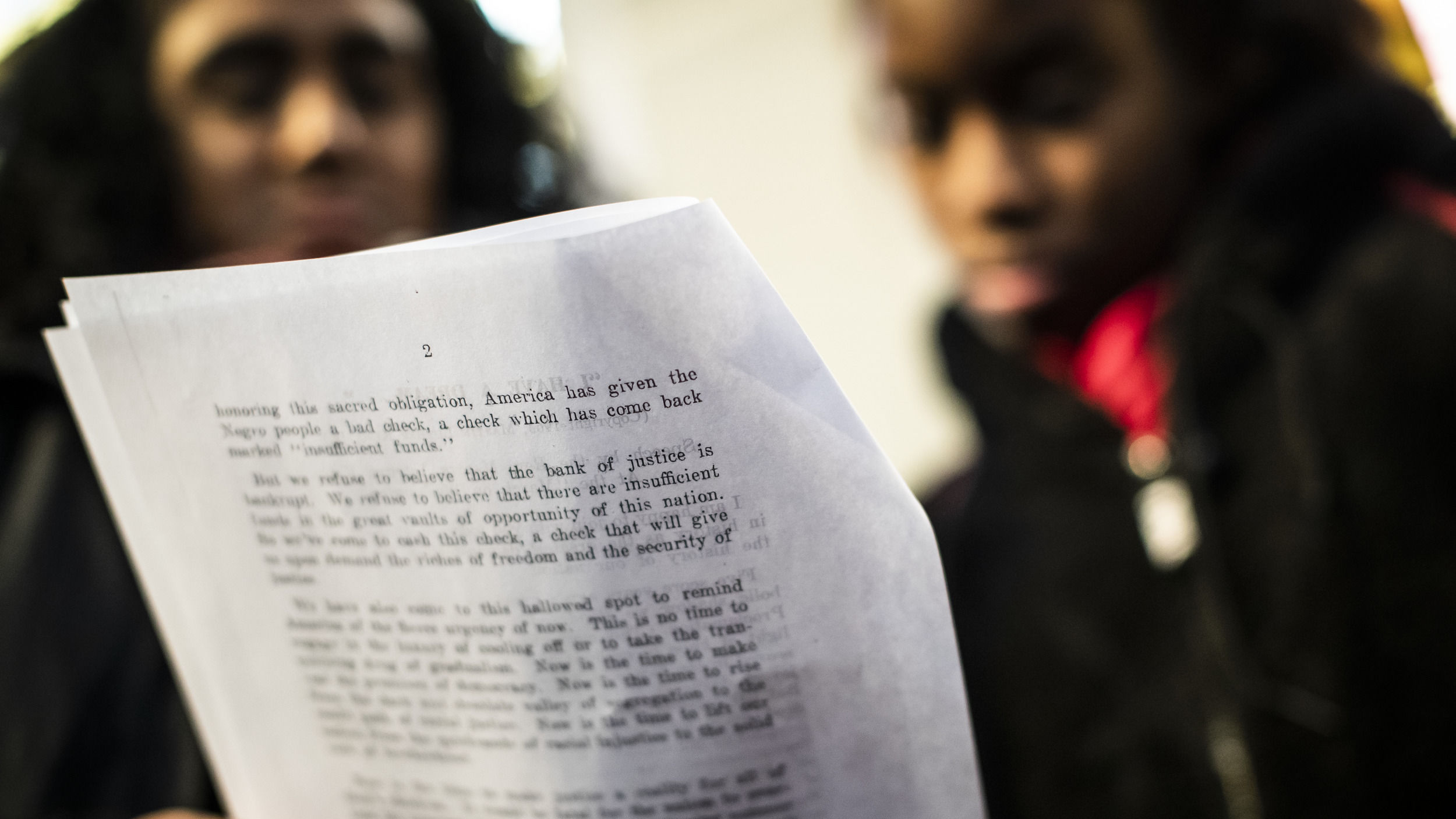 Two Black women read a page from a document together.