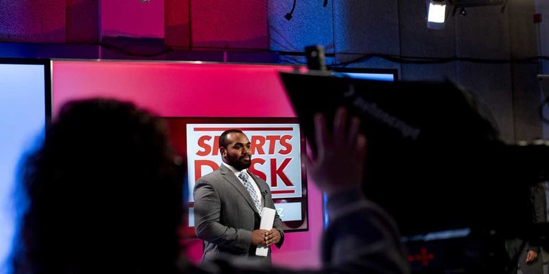 a student in a suit on the set of Sports Desk