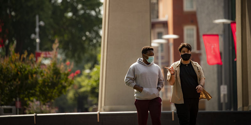Image of two students wearing face coverings walking down Polett Walk on Main Campus.