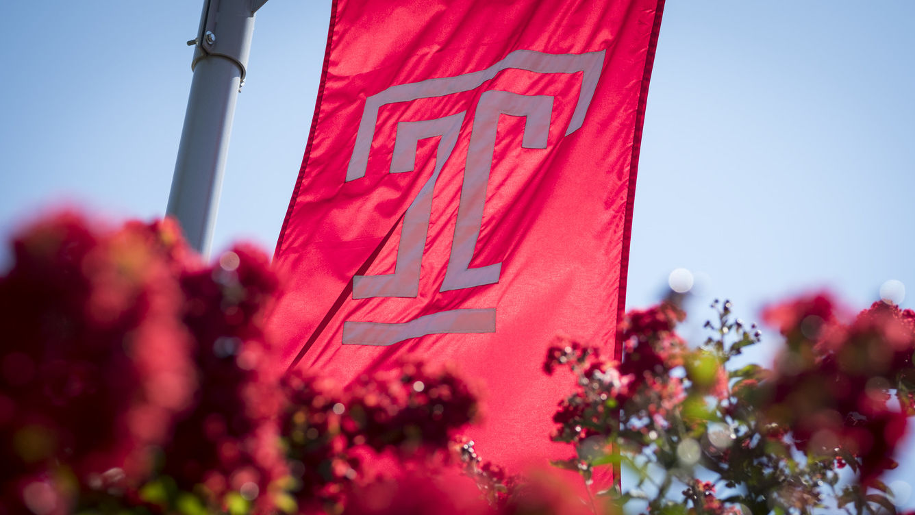 Temple flag flying above red flowers.