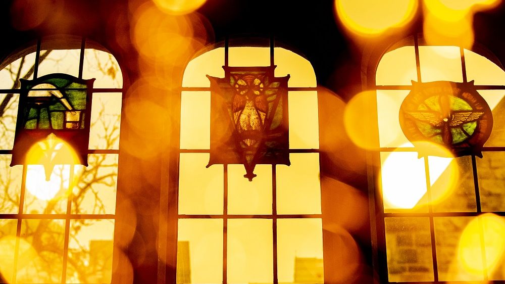 The sun shining through the stained glass windows of Mitten Hall's Great Court. 