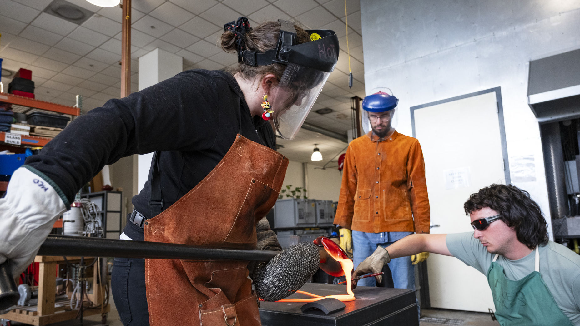 Image of Jessica Jane Julius and two helpers working with molten glass.