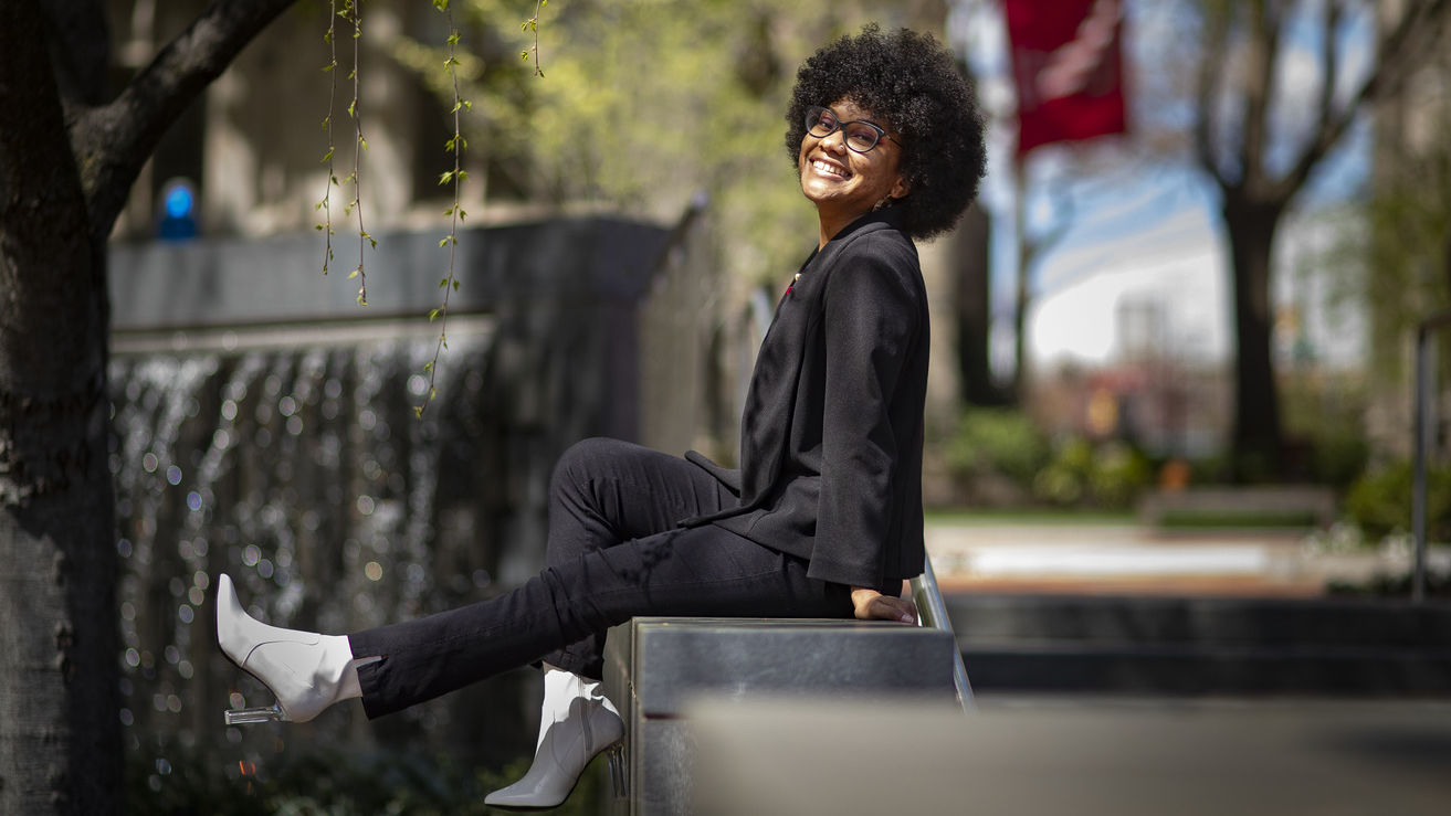 Hall sitting on a railing, kicking out her legs and grinning.