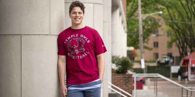 Marcus Forst wearing a Temple basketball shirt in front of Alter Hall
