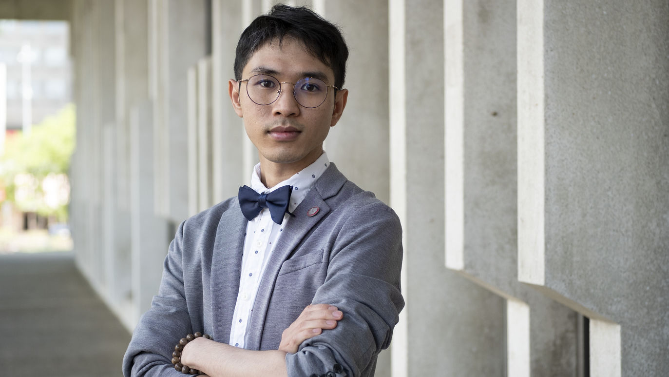 Hoa Vo standing in front of a building, wearing a bow tie.