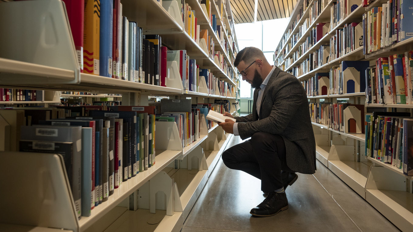 Image of student looking through bookshelves at Charles Library.