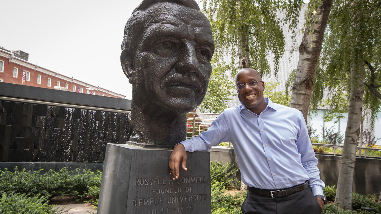 President Jason Wingard stands beside a bust of Temple University founder Russel Conwell.