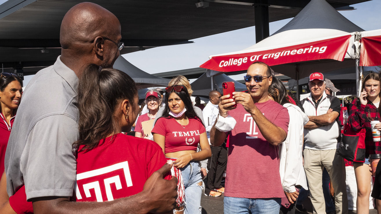 Image of Jason Wingard with a girl wearing a Temple cherry and white tee shirt.