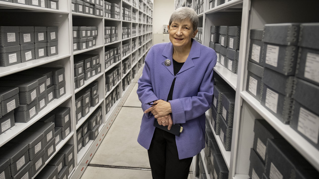 Image of Margery Sly in front of rows of gray boxes.