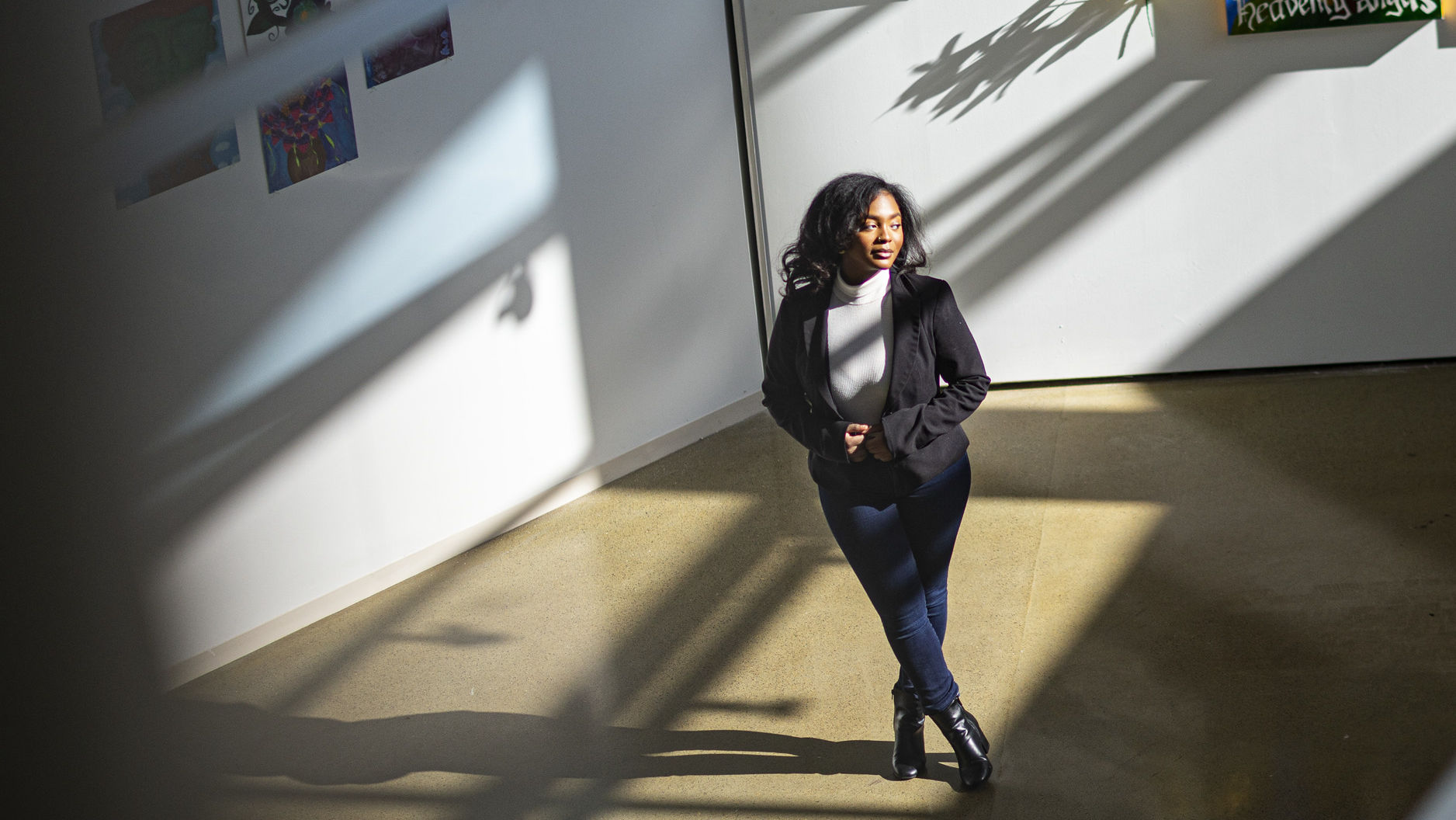 Image of Taylor Sanders standing in front of various paintings.