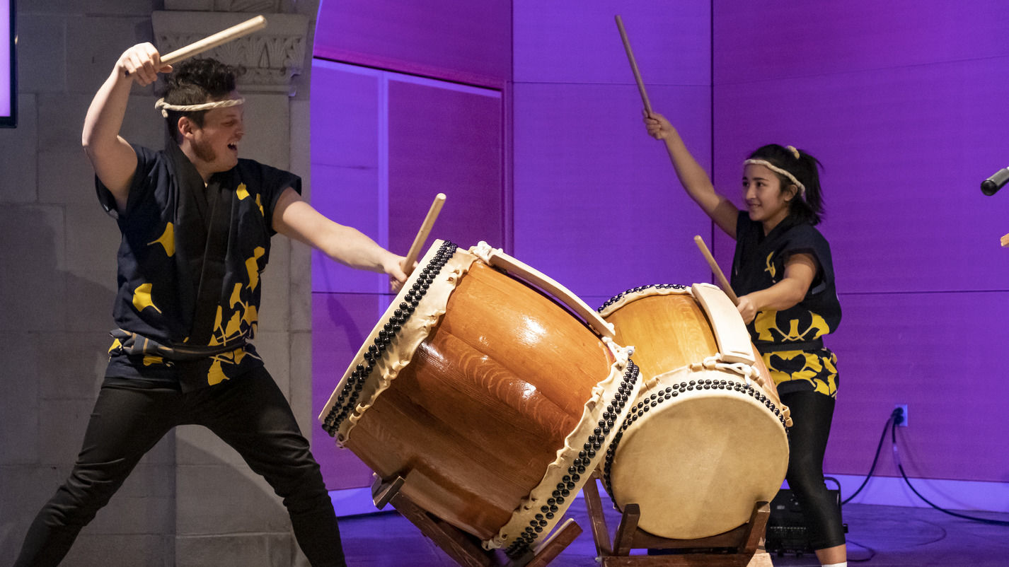 wo students banging on drums as part of a Taiko performance. 