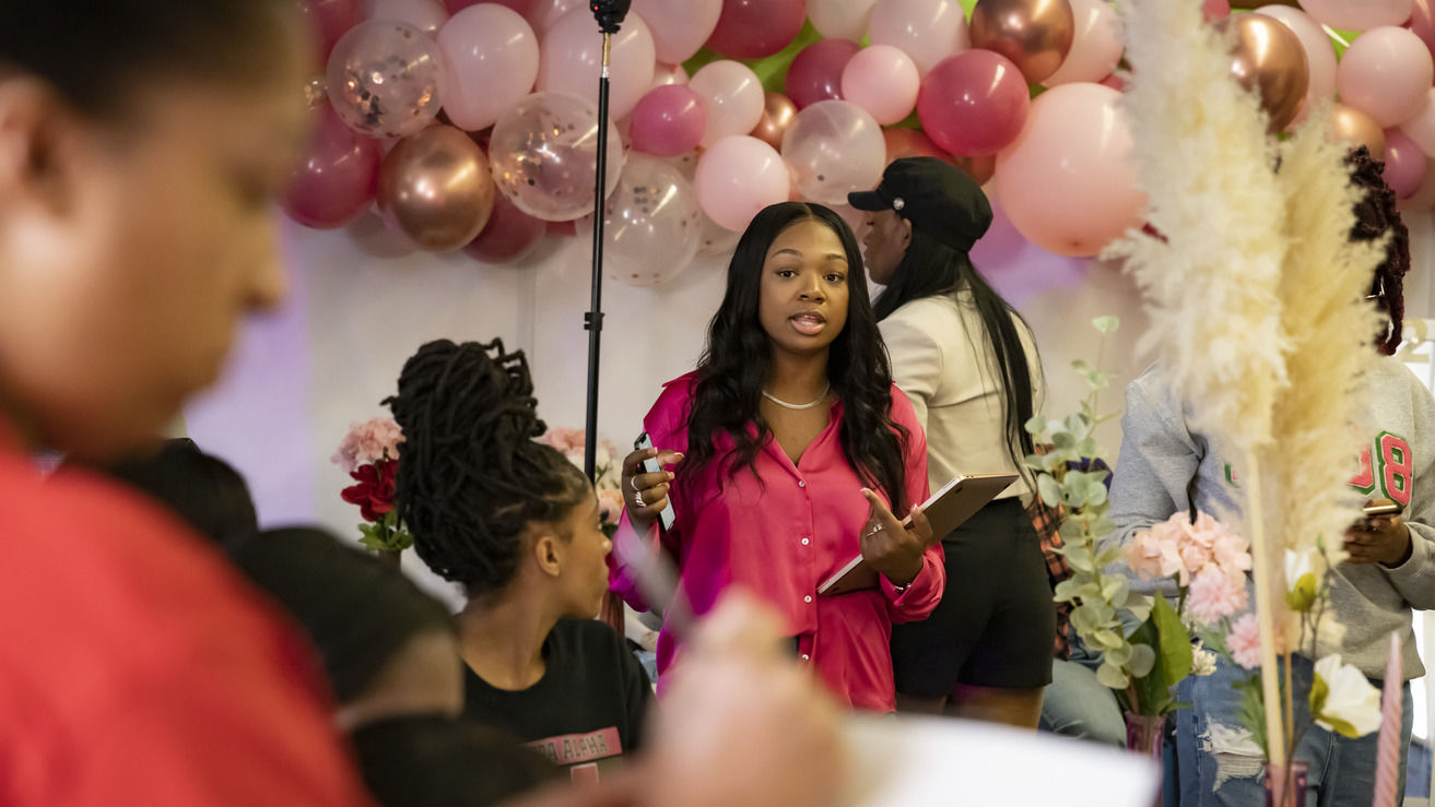  Image of Jaida Ragland  wearing a pink blouse and standing in front of balloons 