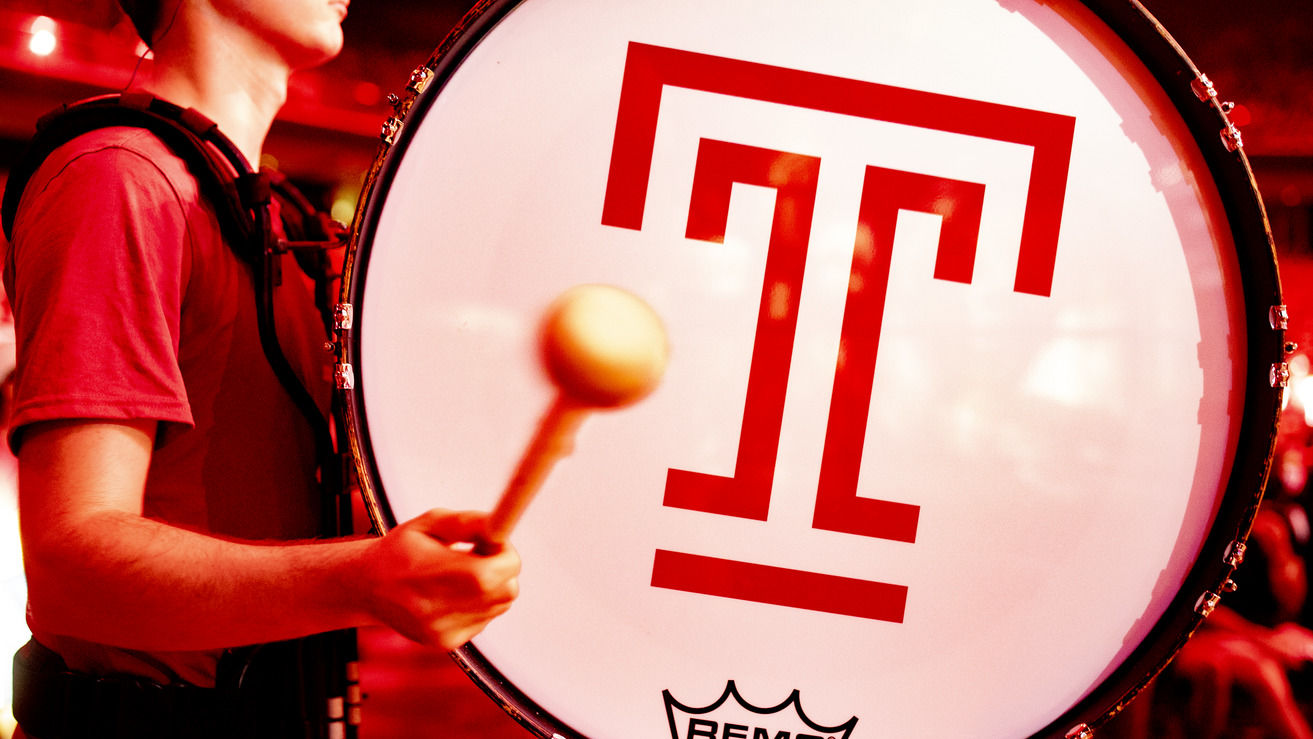 Student playing a drum with a T on it