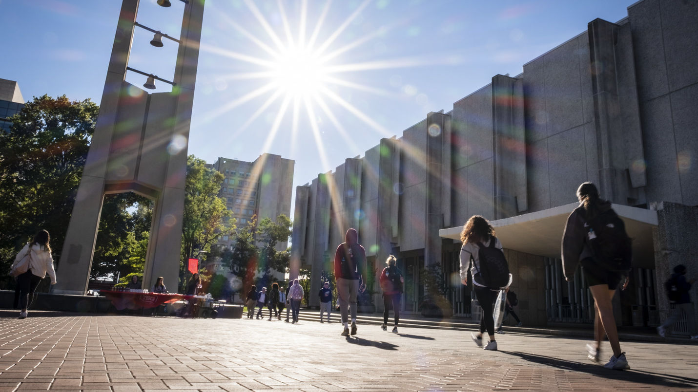 Students walking toward the Bell Tower on a sunny day.