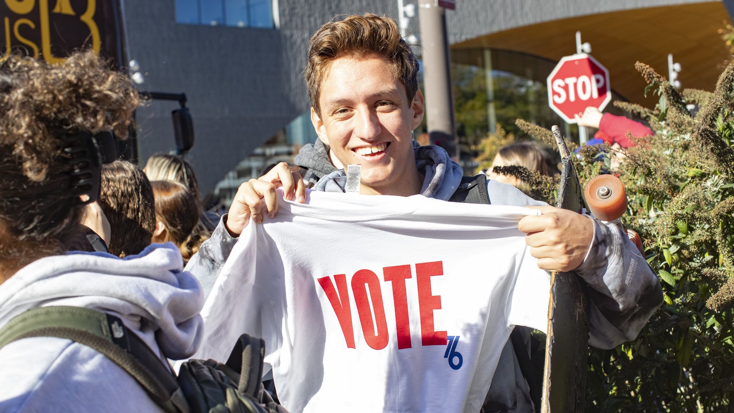 A Temple student holding a t-shirt that says vote