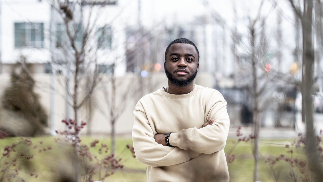 A student in a tan shirt outside in the streets of North Philadelphia.