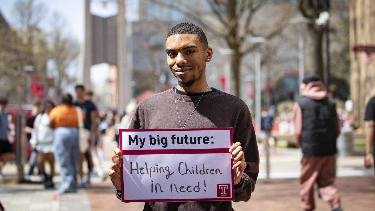 Cameron Barham holding a sign that says Helping Children in need