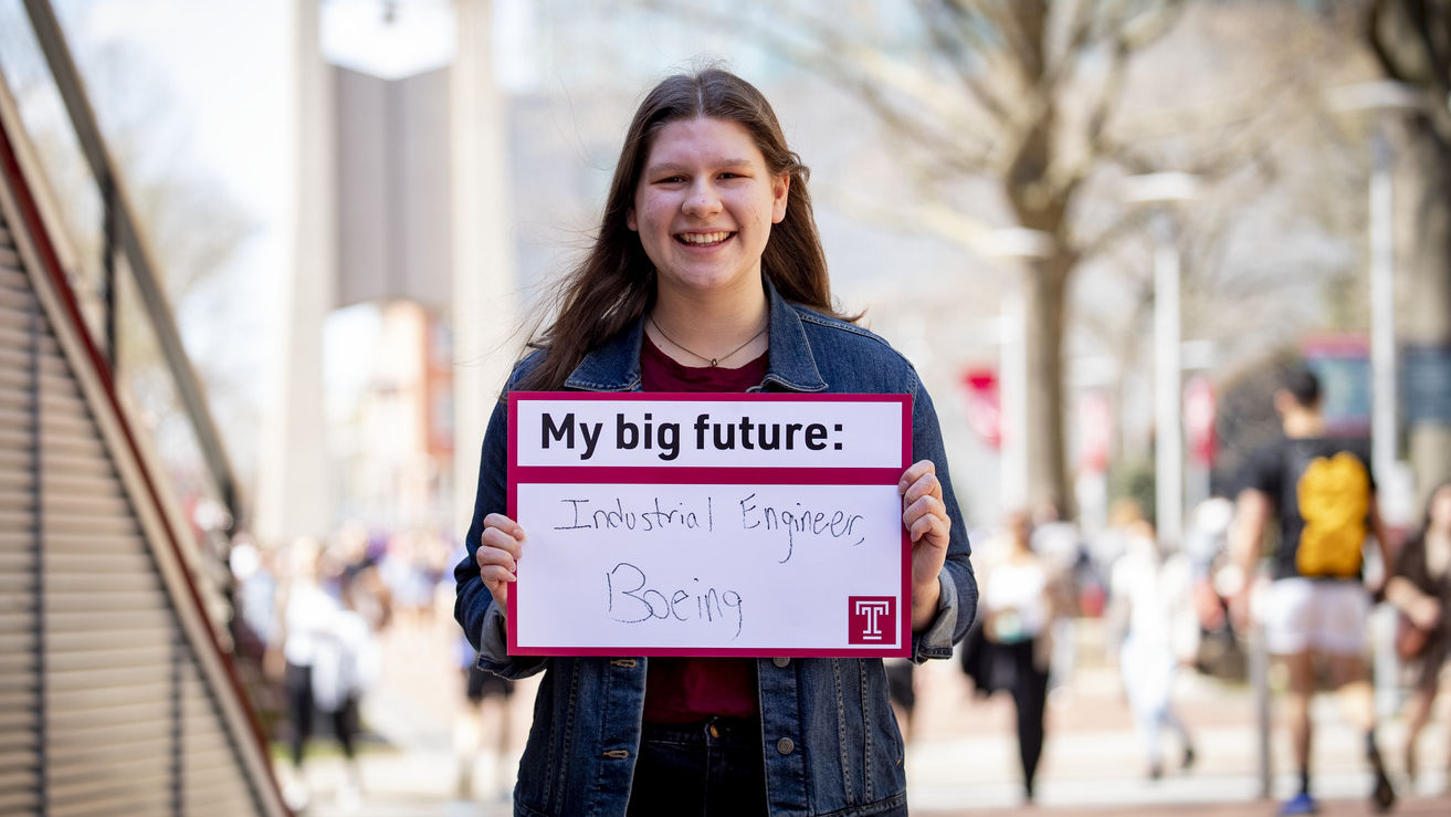 Morgan Schafer outside holding a Big Future sign. 