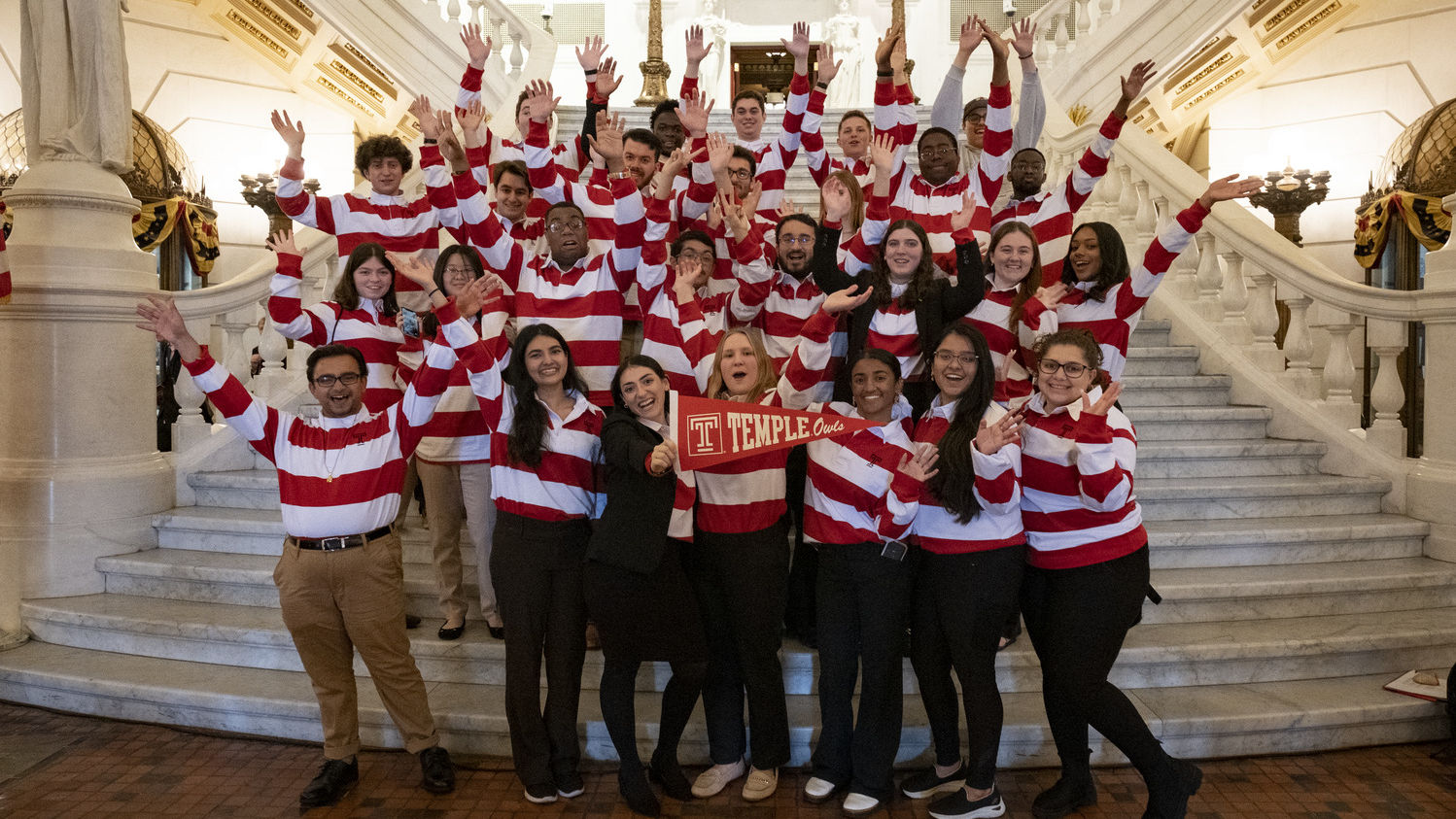 Temple students wearing red and white shirts took a group photo on the steps of the Capitol’s main rotunda. 