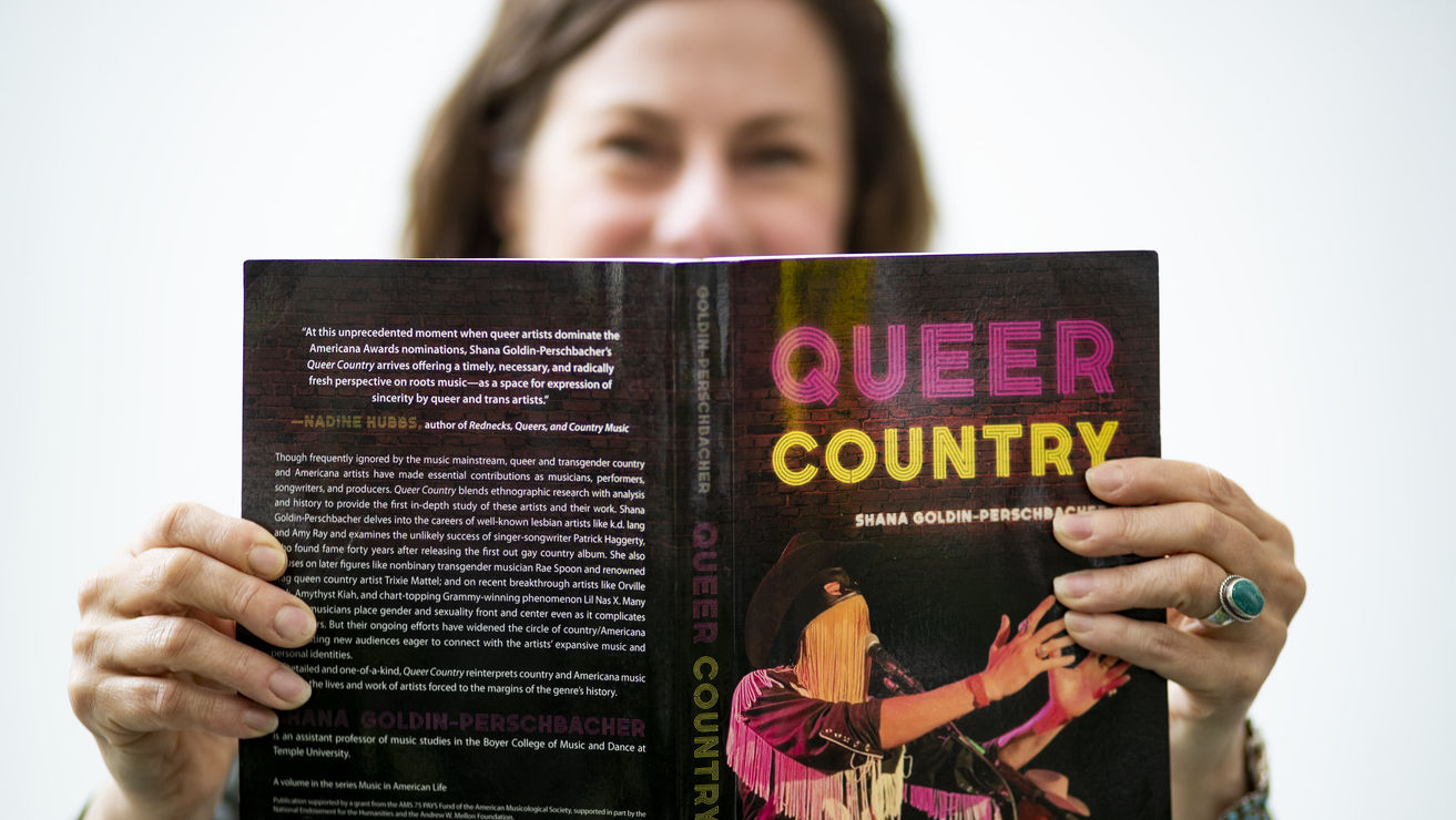 Shana Goldin-Perschbacher holding her book, Queer Country 