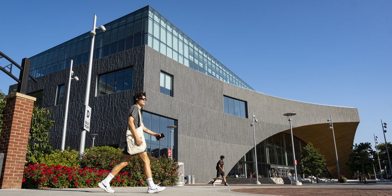 A student walking outside Charles Library.