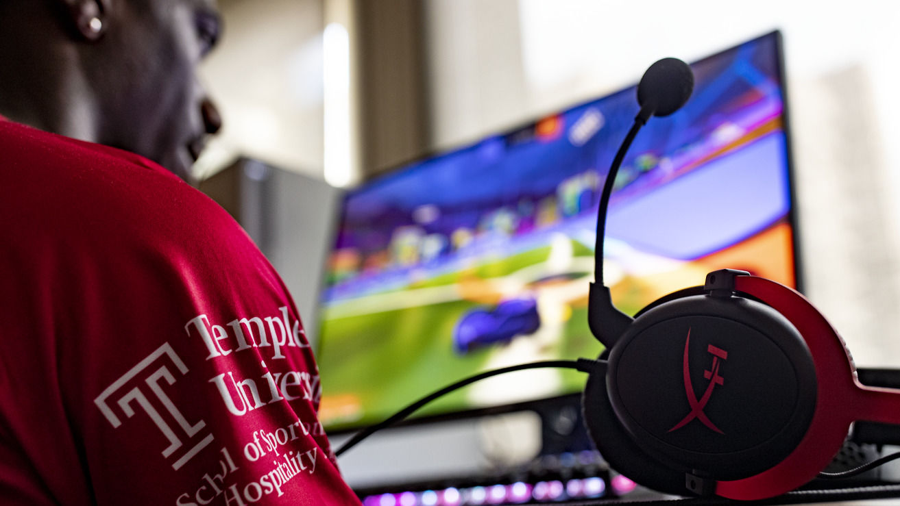Image of a student wearing a Temple esports jersey playing a PC game.    
