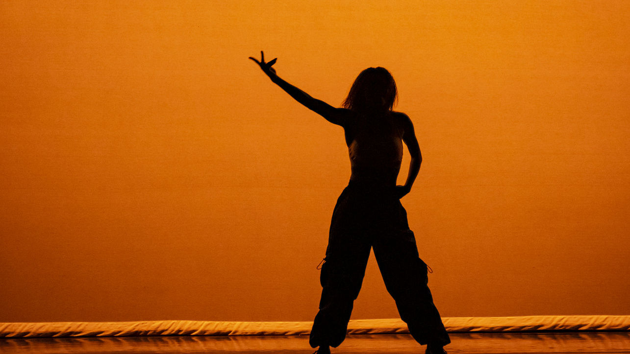 A student's silhouette shown performing at a Temple dance concert