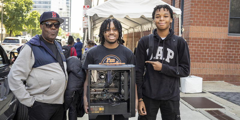 Student holds a computer he built and poses with his family