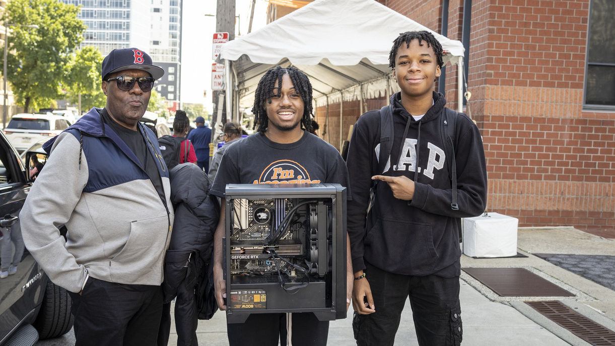 Student holds a computer he built and poses with his family