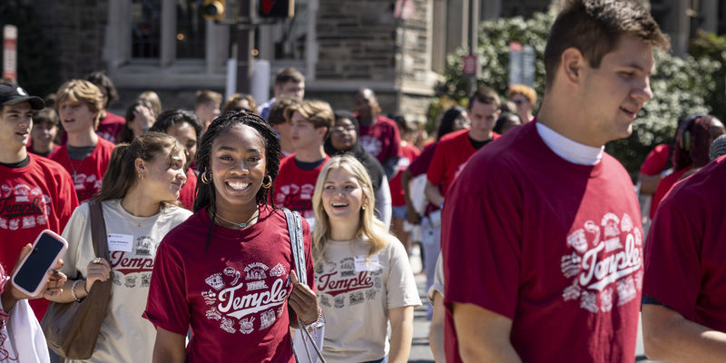 A crowd of smiling students wearing cherry and white t-shirts. 