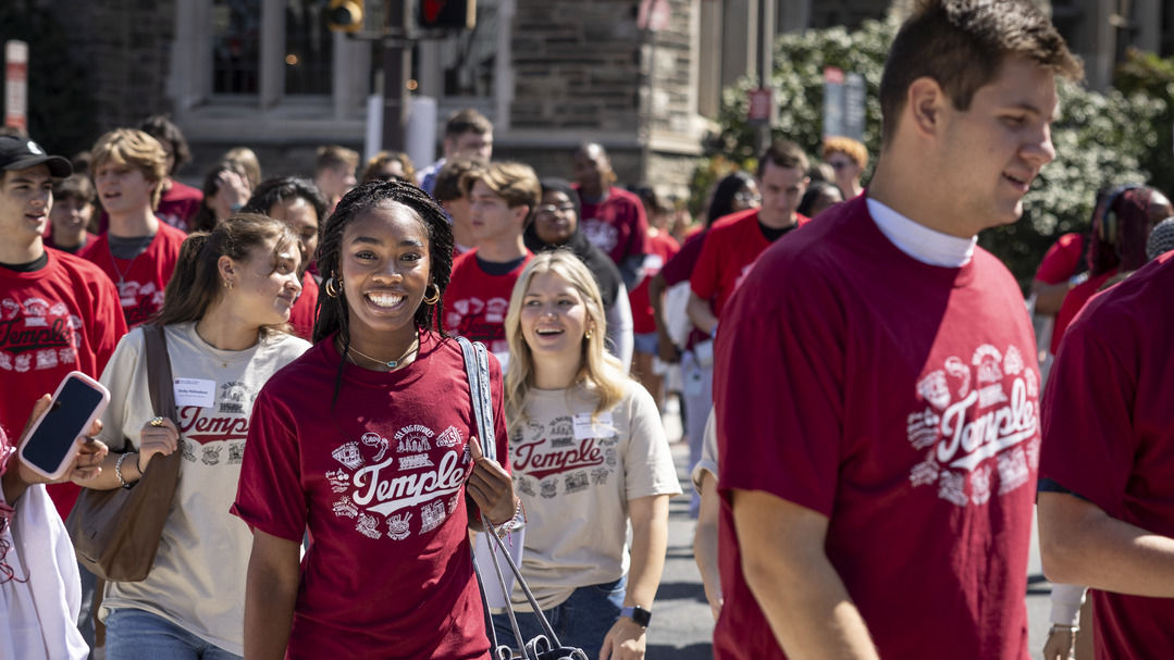 A crowd of smiling students wearing cherry and white t-shirts.