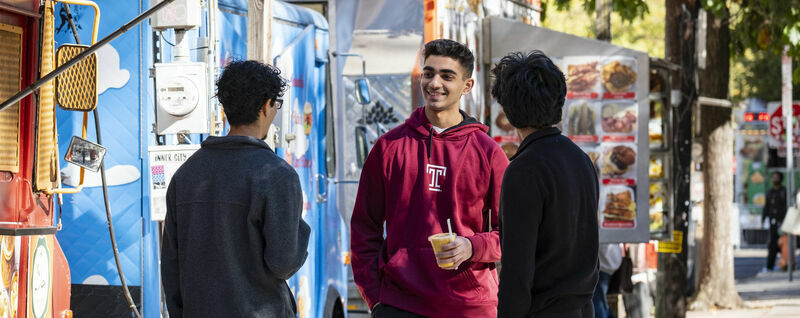 Students standing talking near food trucks on Main Campus