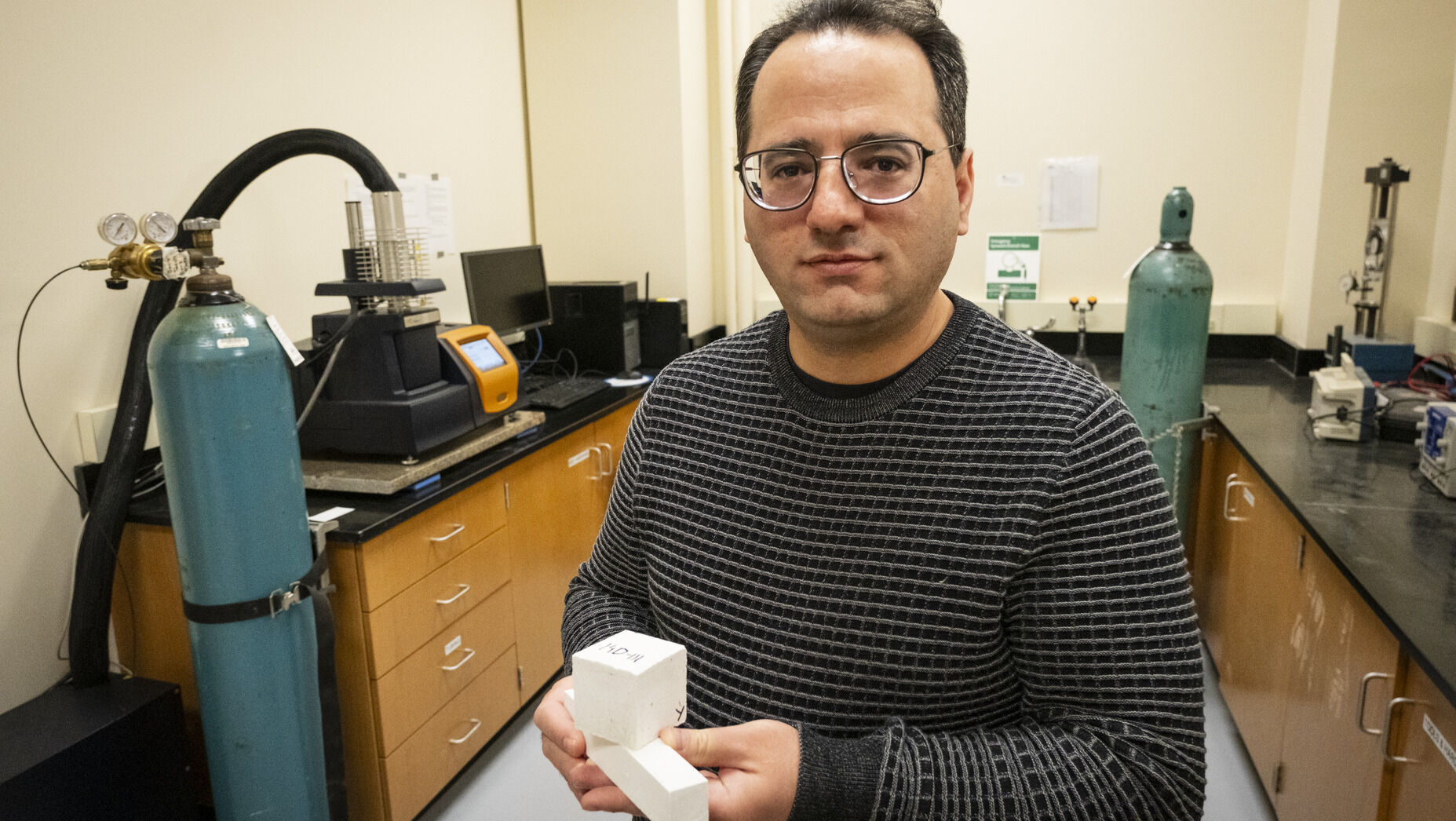 Image of Mehdi Khanzadeh holding a sample of carbonatable concrete.