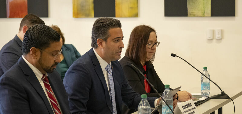 Individuals sitting at a table in front of small microphones