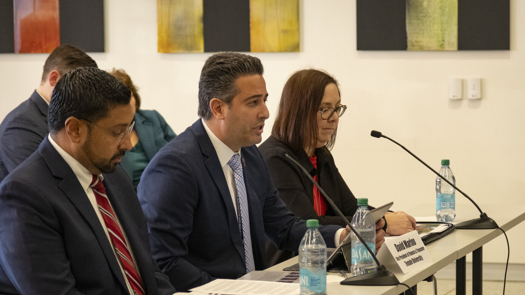 Individuals sitting at a table in front of small microphones