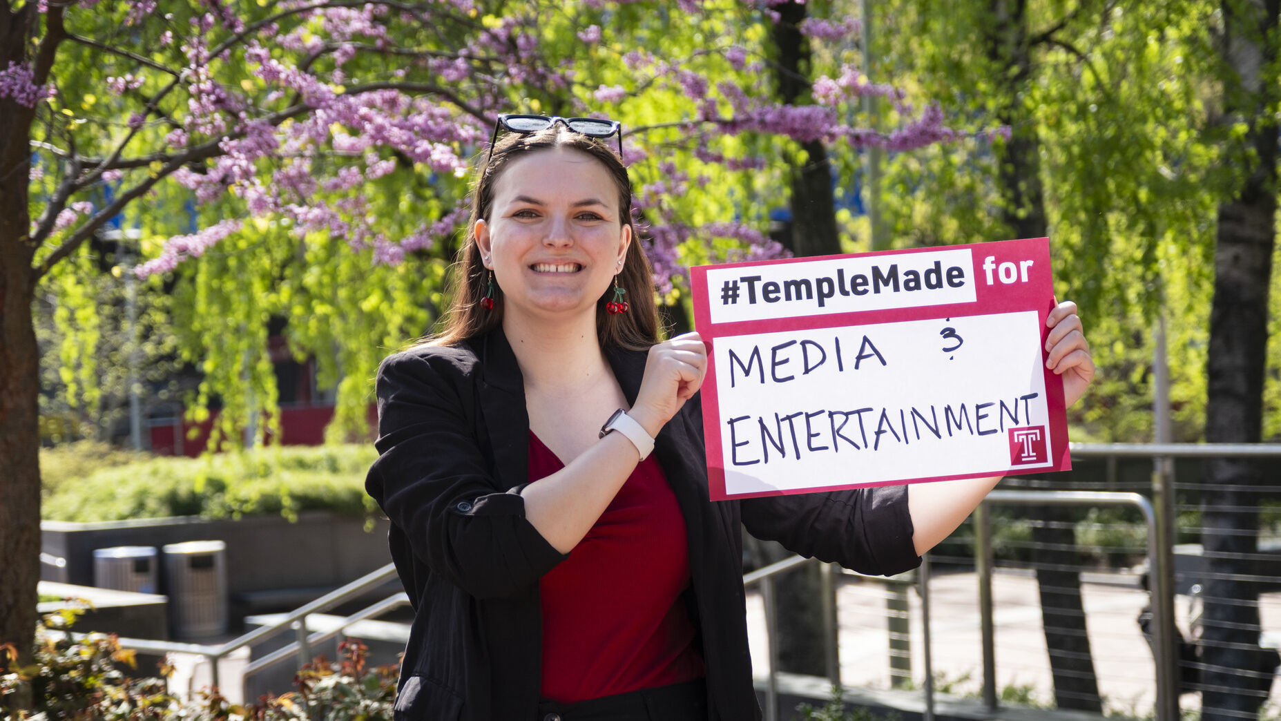 Image of Sydney Binkley holding a sign that reads "media & entertainment."