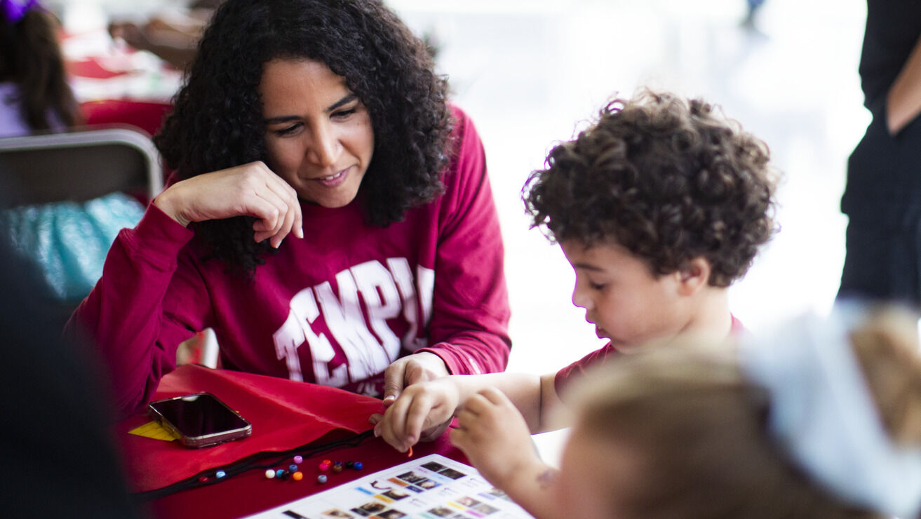 Image of a child with a parent wearing cherry white shirts at Temple.     
