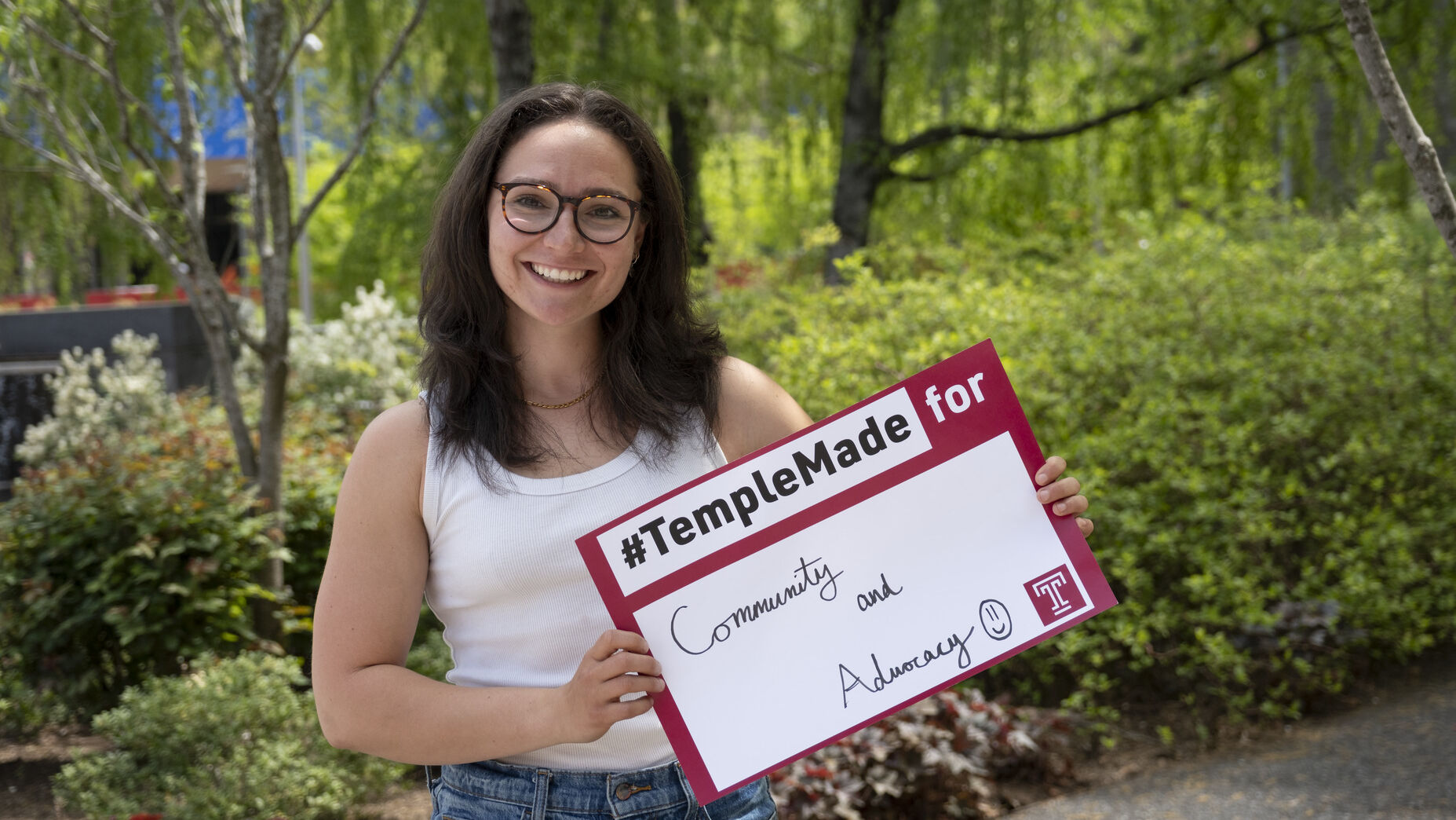 Trista Mayo standing outside holding up a Temple Made for sign