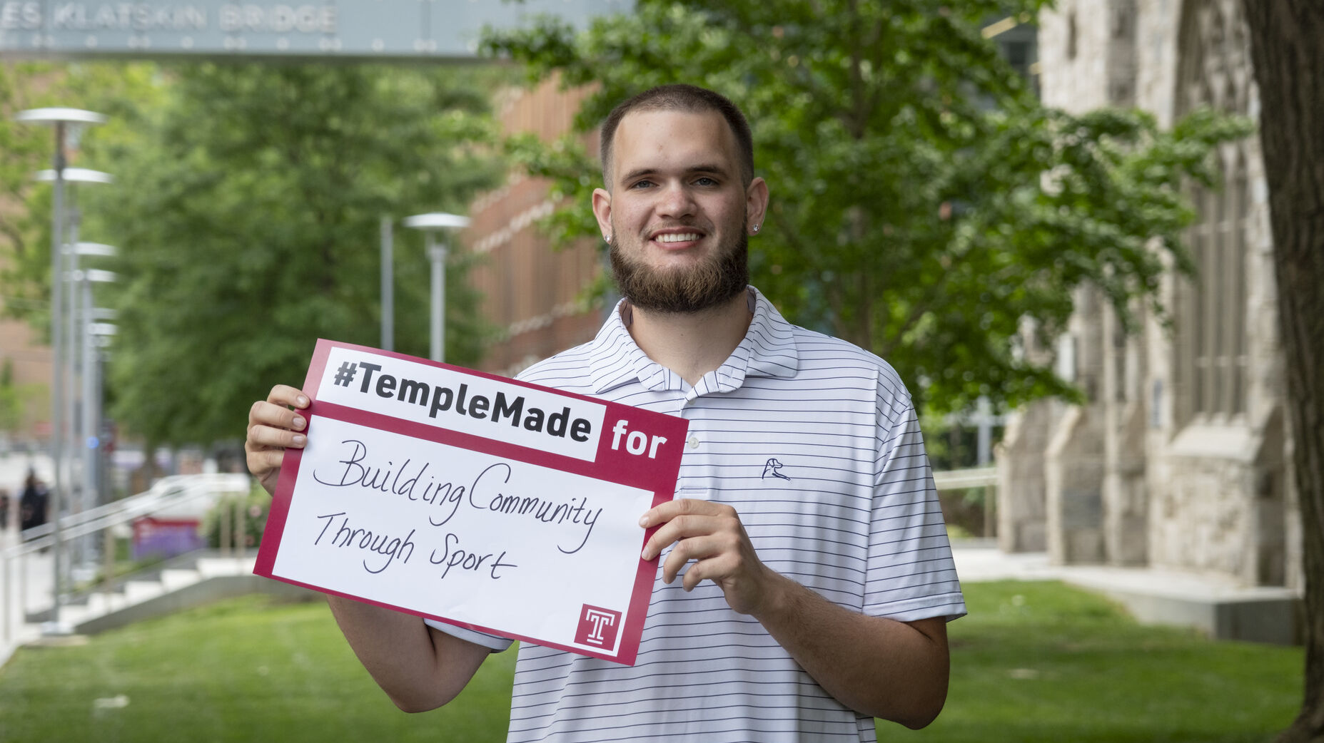 Ezekiel Cartwright standing outside holding up a Temple Made for sign    