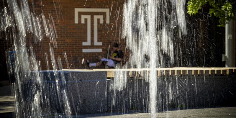 A student is pictured behind a fountain.