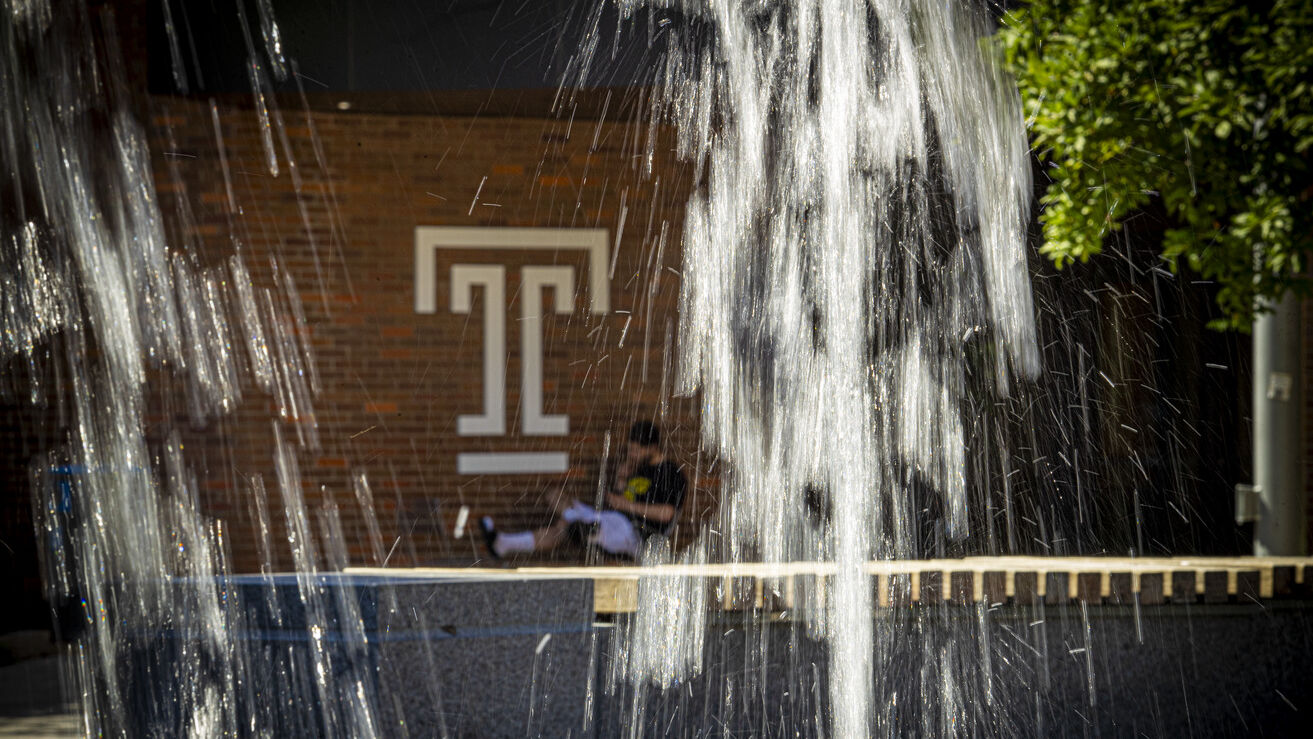 A student is pictured behind a fountain.