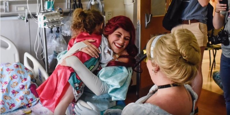 The Mermaid Princess smiles as she hugs a child in a hospital room