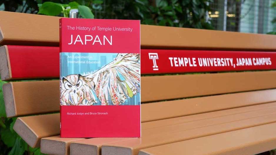 A copy of  The History of Temple University Japan on a bench 