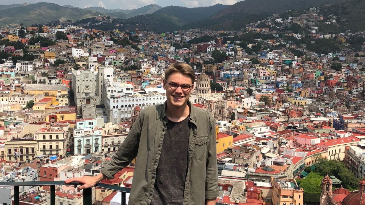 Alex Voisine standing in front of a cityscape. 