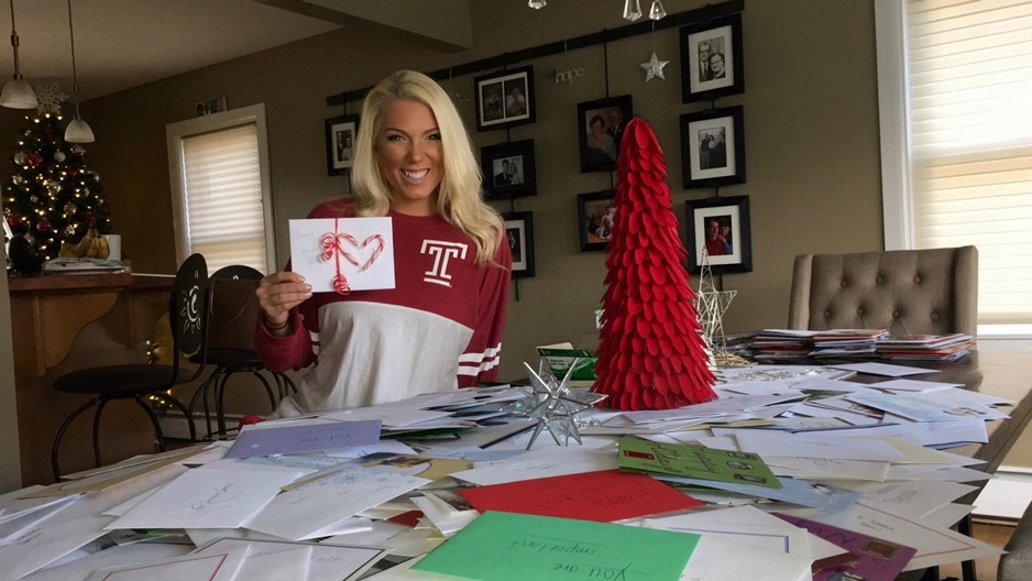 student Alison Boettlin holding up a holiday card with candy canes on it.